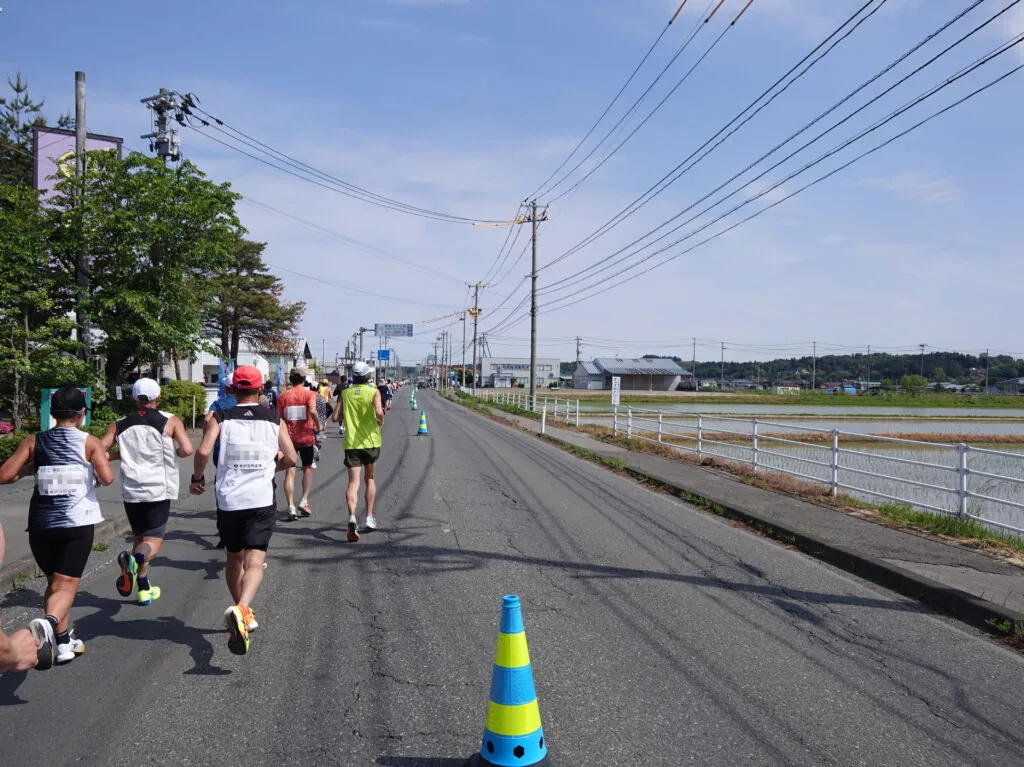 電線が空に伸びる広い道を走るランナーたち