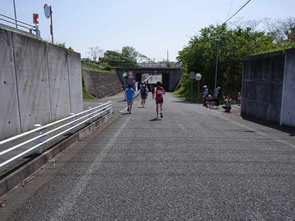 沿道の声援を受けながら小さなトンネルへ向かうランナーたち