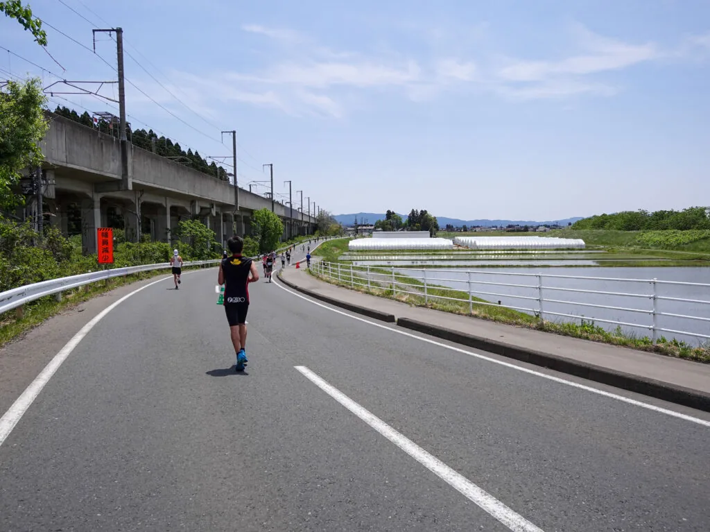 高架の線路の脇を走るランナーたち