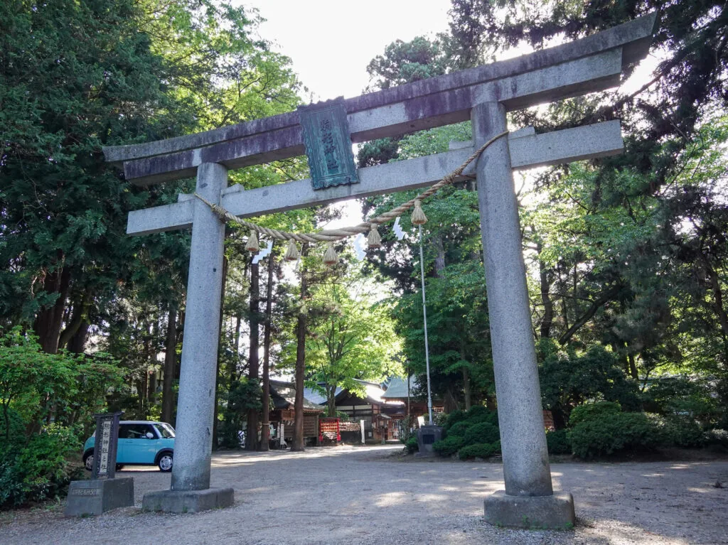 注連縄が掛かる石の鳥居と、木立の奥の境内（駒形神社）